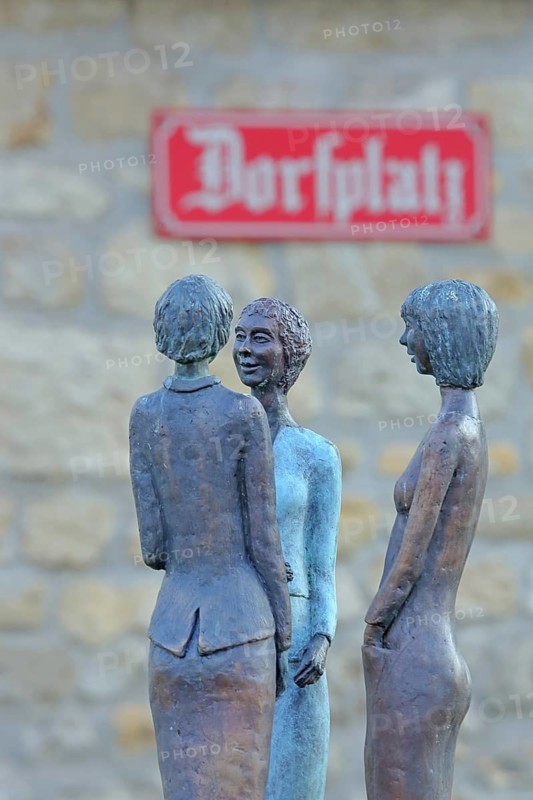 Sculpture Dorfgeflüster by Rosi Röhm 2021, bronze sculpture, three slender female figures in rural conversation, whispering, whispering, talking, speaking, communication, interaction, chatting, discussing, gossiping, telling, chatting, chatting, talking, conversation, female figure, graceful, inscription, street name, sign, rural, village, rural, symbol, village, place, village square, Drais, Mainz, Rhine-Hesse region, Rhineland-Palatinate, Germany