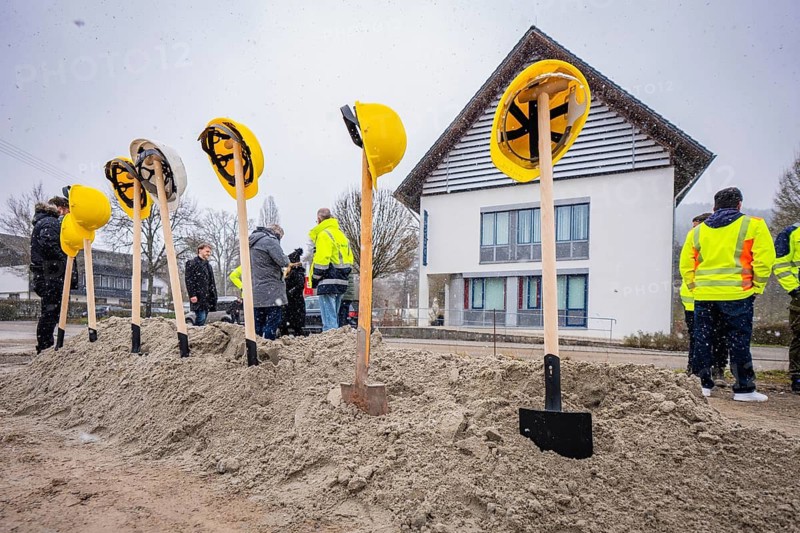 Yellow helmets on spades stuck in a pile of sand, with people and buildings in the background, fiberglass groundbreaking, Glatten, Freudenstadt district, Germany