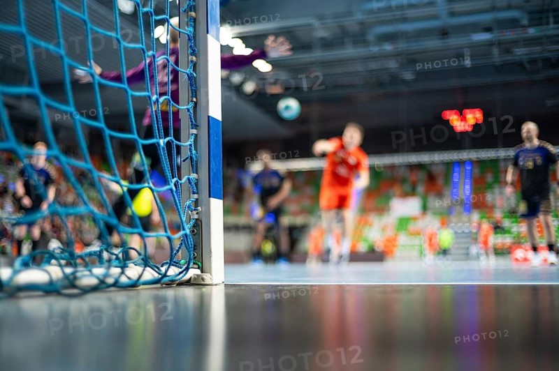 Detail of handball goal post with net and handball match in the background in Lubin, Poland