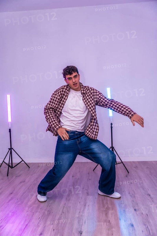 Energetic dancer showcasing urban dance moves in a studio illuminated by vibrant led lights, expressing passion and rhythm