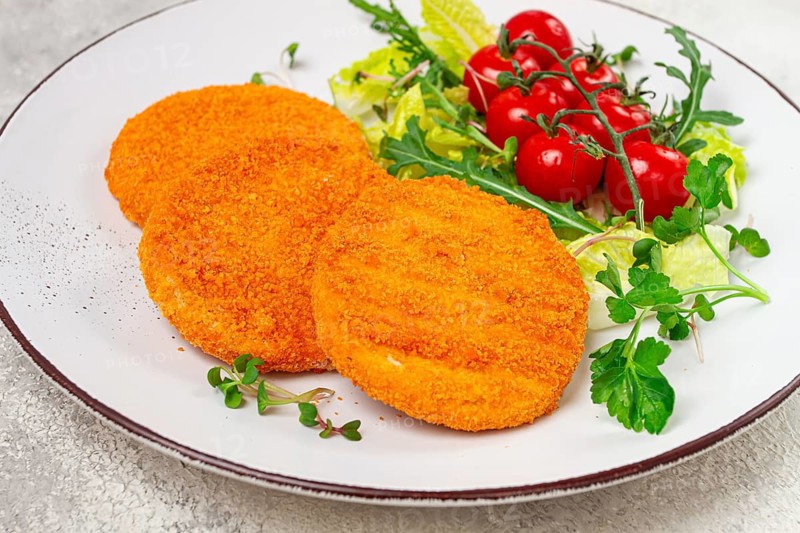 Crispy fried fish cutlets, fish burgers, on a white plate, with fresh lettuce leaves, arugula and cherry tomatoes, homemade, no people