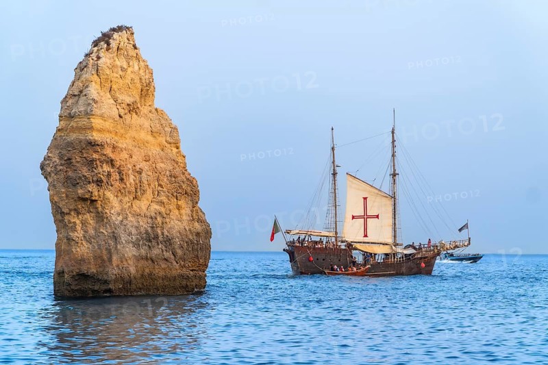 Tourists enjoying a leisurely cruise on a traditional portuguese caravel, passing majestic rock formations in the stunning algarve region of portugal