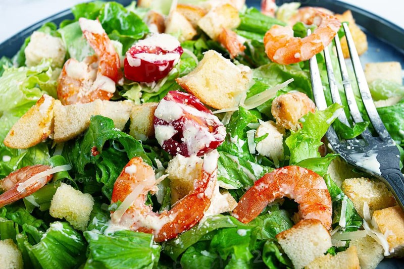 Caesar salad, with shrimp, on a marble background, top view, no people