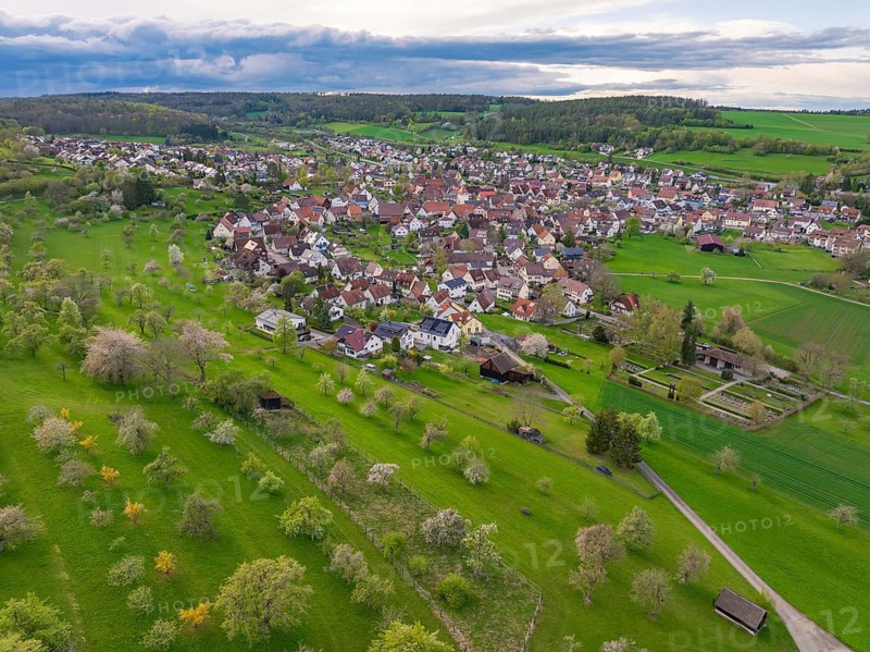 Idyllic landscape with a village and orchards under a partly cloudy sky, Ostelsheim, district of Calw, Germany