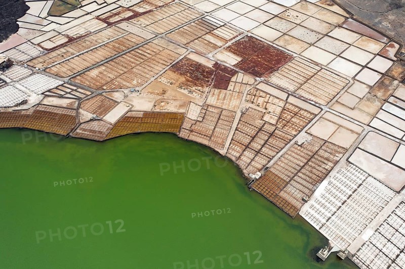 Vibrant aerial shot capturing the diverse color palette of the Los Salares de Janubio in Lanzarote, with its unique green waters and geometric salt evaporation ponds