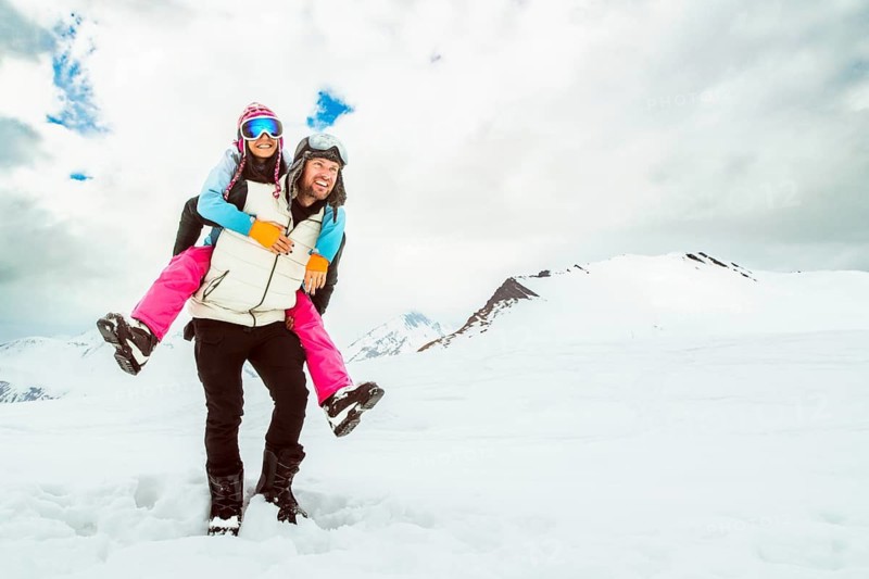 Excited young Playful couple piggyback enjoy winter time together outdoors in snowy landscape together, happy romantic moment in mountains.Winter holidays vacation outdoors winter wonderland