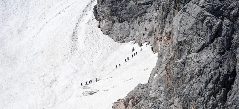 Mountaineers queuing at the transition from the Höllentalferner to the Zugspitz via ferrata, on a snowfield, overtourism, mountain basin with glacier remnant of the Höllentalferner, Höllental, rocky mountain peaks, Höllental, Bavaria, Germany