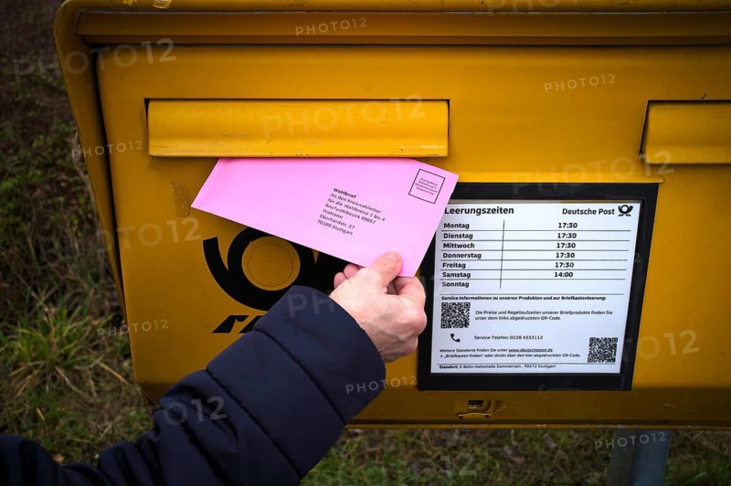 Woman throws ballot letter into mailbox, ballot envelope, bright red, pink, postal ballot, official absentee ballot documents, election, parliamentary election, state election 2026, Stuttgart, Baden-Württemberg, Germany