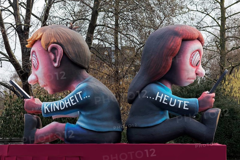 Two young people stare at the cell phone, childhood today, social media addiction, social media ban, theme car by wagon manufacturer Jacques Tilly, Düsseldorf Rose Monday train, Düsseldorf, North Rhine-Westphalia, Germany