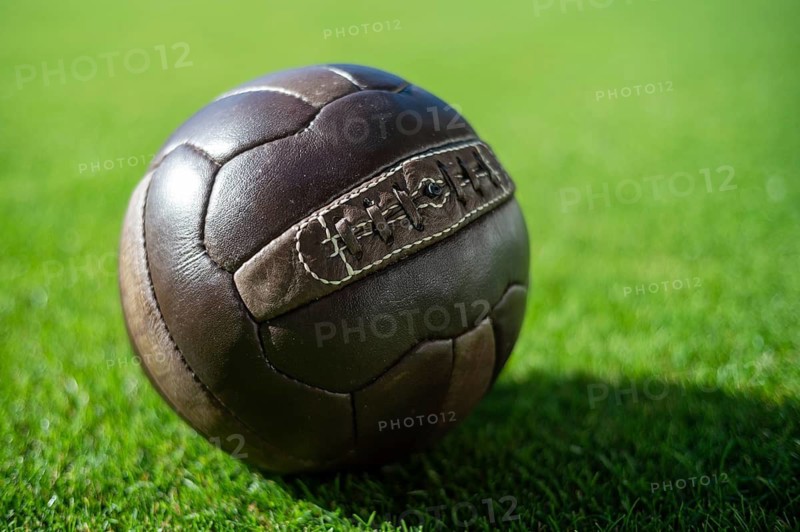 Old soccer leathe ball on the grass