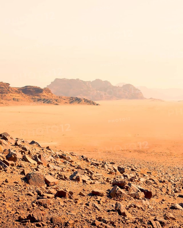 Expansive barren desert of Wadi Rum in Jordan with red sand, rocky terrain, and distant mountains. UNESCO World Heritage site, famous filming location for science fiction movies such as The Martian and Dune