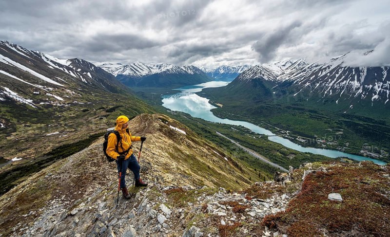 Climbers on a hiking trail on Slaughter Ridge, views of snowy mountains in spring and turquoise Lake Kenai Lake, Cooper Landing, Kenai Peninsula, Alaska, USA