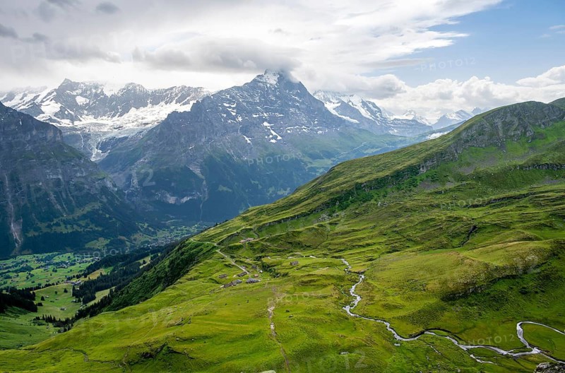 View of mountain landscape with green meadows and alpine huts Bachlager, Grindelwald First, snow-capped Eiger mountain peak, Grindelwald, Bernese Alps, Bernese Oberland, Switzerland