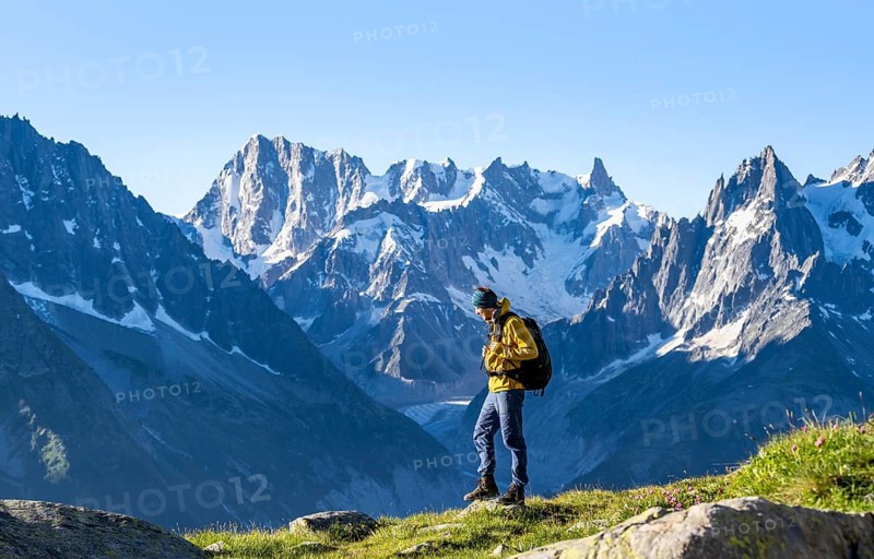 Young man in front of impressive mountain landscape in morning light, picturesque mountain landscape with imposing mountain peaks and glaciers, Mer de Glace glacier, Grandes Jorasses in the background, Mont Blanc Massif, Chamonix-Mont-Blanc, Haute-Savoie, France