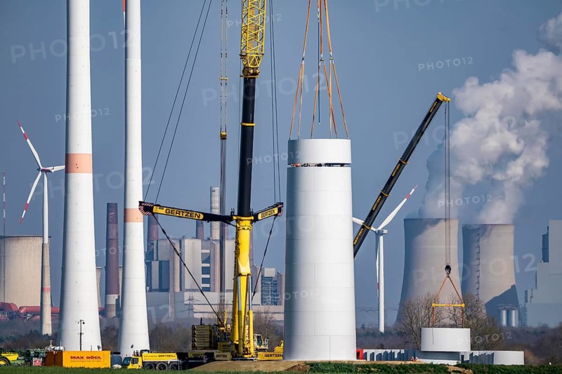 Construction site of the new Bedburg 3 wind farm, on recultivated open-cast mining site, 9 wind power plants with an output of 60 megawatts are newly built, installation of the wind turbine tower, in the background the Neurath lignite power plant, operated by RWE and the city of Bedburg, North Rhine-Westphalia, Germany