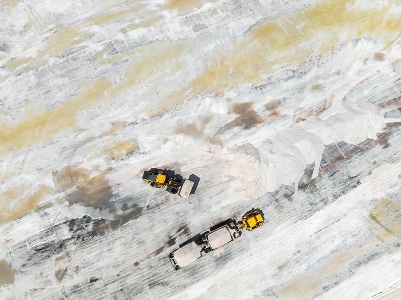 Excavator and lorry at a harvesting pan of the Walvis Bay Salt works. Aerial view. Drone shot. Walvis Bay, Namibia