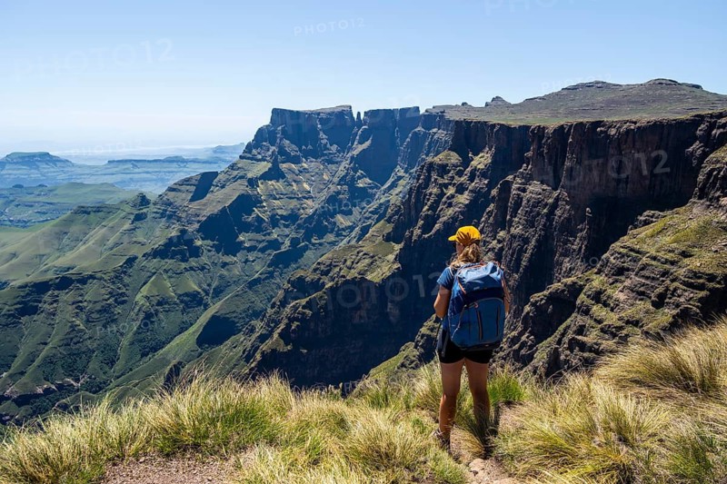 Young hiker looking at the impressive mountains and cliffs of the Drakensberg Mountains, hiking trail on the Sentinel Hiking Trail, Drakensberg, KwaZulu-Natal, South Africa