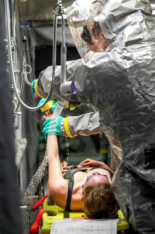 Decontamination of injured persons after an assumed accident involving hazardous substances, fire brigade and aid organisations practise setting up and operating a decontamination station, injured persons are sighted and then washed in a special shower tent to remove possible hazardous substances and chemicals in order to avoid further injuries, the emergency services wear special, ventilated protective suits, large-scale exercise by the Essen fire brigade