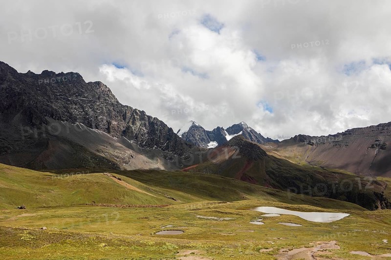 Captivating view of Ausangate mountain in the Andes of Peru, showcasing rugged peaks and serene alpine lakes amidst vibrant greenery