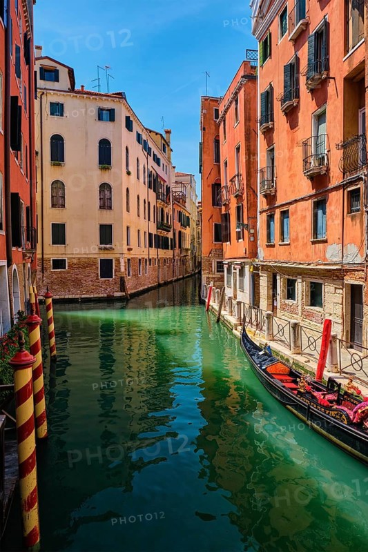 Narrow canal between colorful old houses with gondola boat in Venice, Italy