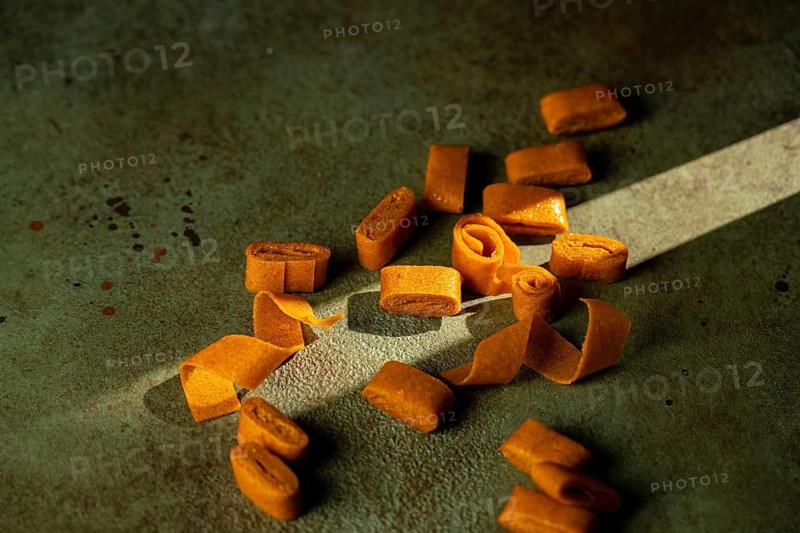 Sea buckthorn and apple fruit leather rolls are showcased on a textured surface. These natural snacks offer a blend of sweet and tangy flavors, perfect for healthy snacking