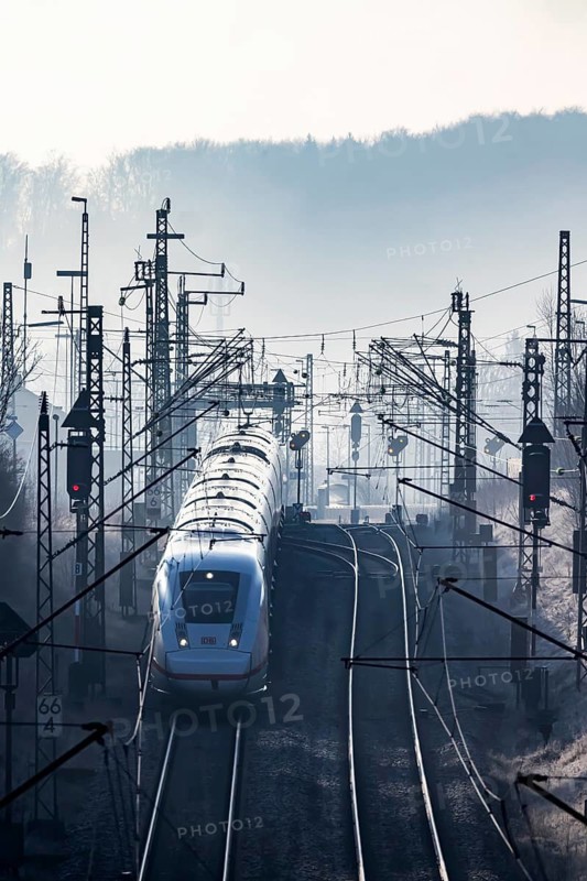 Deutsche Bahn AG tracks with ICE train against the light. Overhead line, signals and infrastructure. Railway tracks at the Geislinger Steige, Alb ascent to the Swabian Alb. Amstetten, Baden-Württemberg, Germany