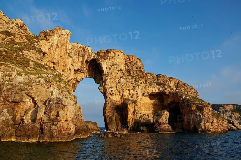 An impressive rock arch rises from the sea, morning light, Tsichli Babas islet, Navarino Bay, Pylos, Peloponnese, Greece