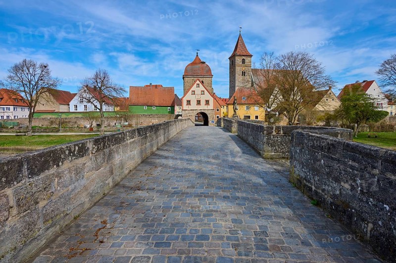 View along a historic stone bridge with cobblestones to a village with church and city gate, Frühling, Ornbau, Triesdorf, Franconian Lake District, Ansbach District, Middle Franconia, Bavaria, Germany