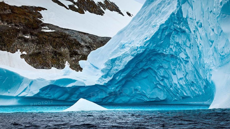 An impressive mixture of ice and rock, a huge iceberg off a snow-covered coast, icebergs in the Southern Ocean in Antarctica