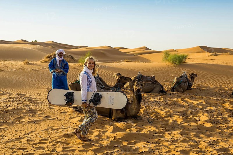 Young woman with snowboard in the sand dunes, near Merzouga, Meknès-Tafilalet region, Erg Chebbi, northern Sahara, Morocco
