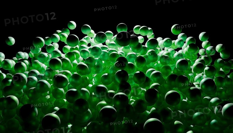 A dynamic collection of glowing green spheres set against a dark background, creating an abstract and visually striking design with a sense of movement and depth