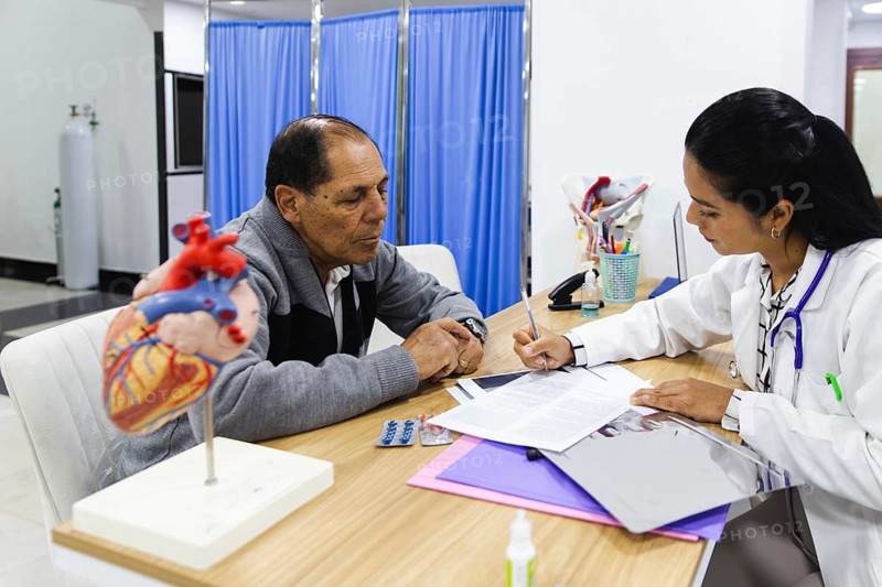 An elderly male patient receives professional medical attention from a young female doctor inside a Latin American hospital, illustrating compassionate healthcare services