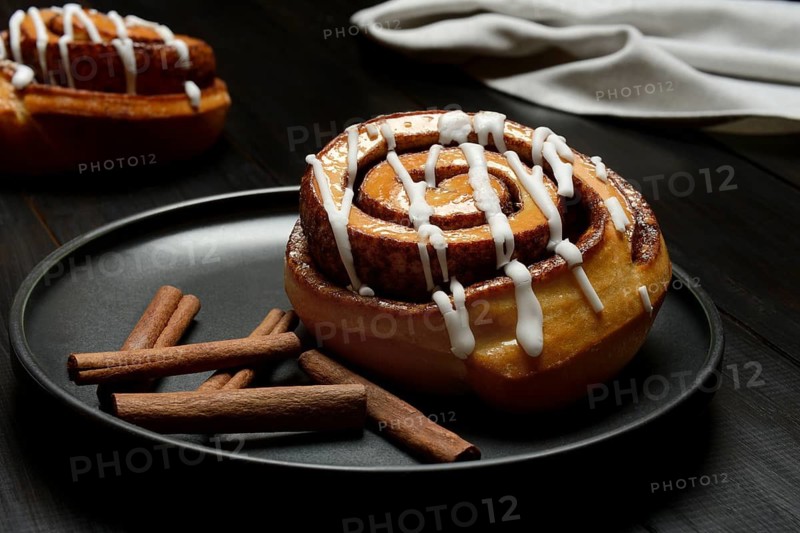 Cinnamon roll on plate and cinnamon sticks