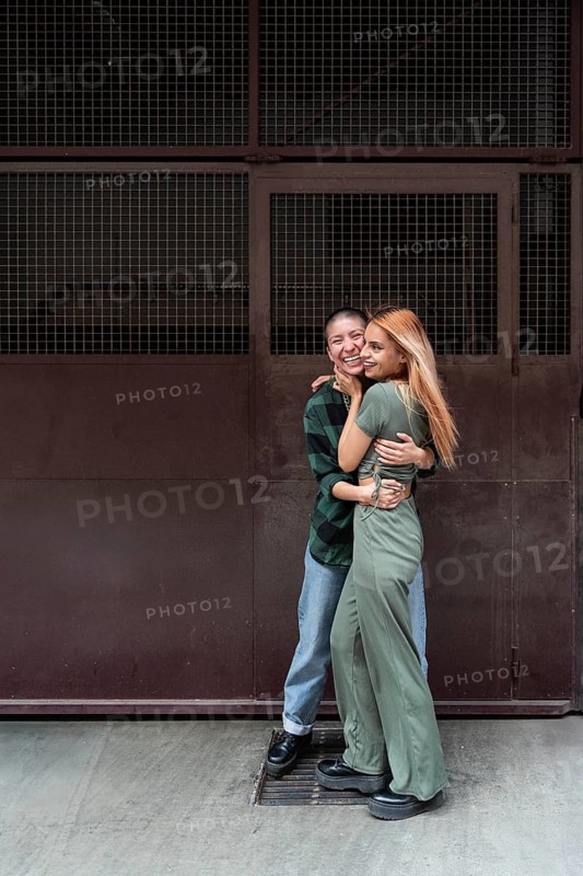 A joyful Colombian lesbian couple sharing an embrace against an urban backdrop, symbolizing love, diversity, and acceptance within the LGBTQIA+ community
