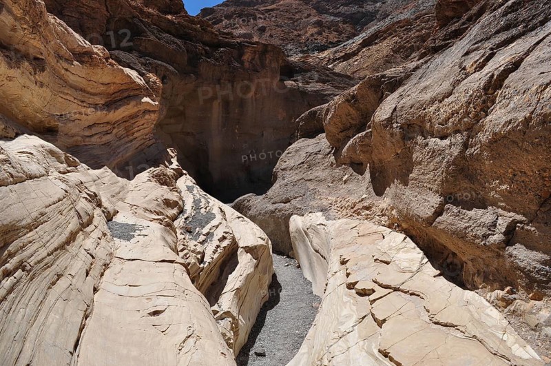 Narrow passage of a hiking trail between tall rocks with deep shadows and steep walls, Death Valley National Park, Mojave Desert, California, Nevada, USA