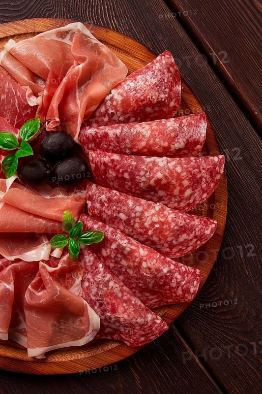 Assortment, sliced meat appetizer, prosciutto, salami and ham, with olives, breakfast, top view, close-up, no people