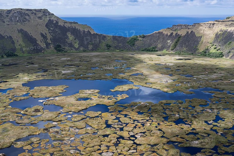 Rano Kau volcano crater lake with floating Totora reed islands, view across the crater rim to the Pacific Ocean, Rapa Nui National Park, Easter Island, Chile