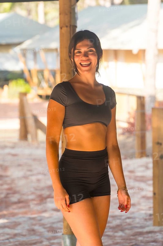Yoga instructor smiling and starting a meditation session in a glamping resort, wearing black activewear, promoting healthy lifestyle and wellness tourism