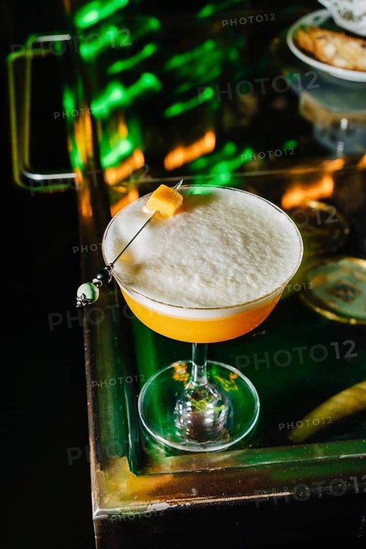 A beautifully crafted peach cocktail viewed from above, showcasing its frothy texture and delicate garnish