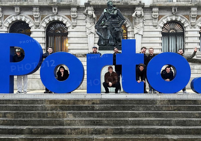 Large, blue postage lettering in front of the town hall with men posing, group photo in front of the statue of Almeida Garret by Barata Feio, Porto, Portugal