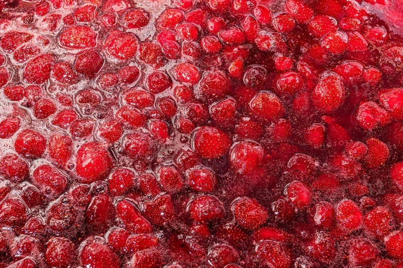 A close up image of vibrant homemade strawberry jam, showcasing the rich texture and color of fresh strawberries and sugar, perfect for breakfast spreads or baking