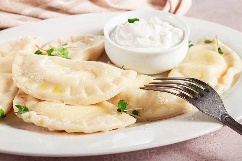 Traditional Georgian kvari dumplings, served with sour cream and herbs, close-up view, no people