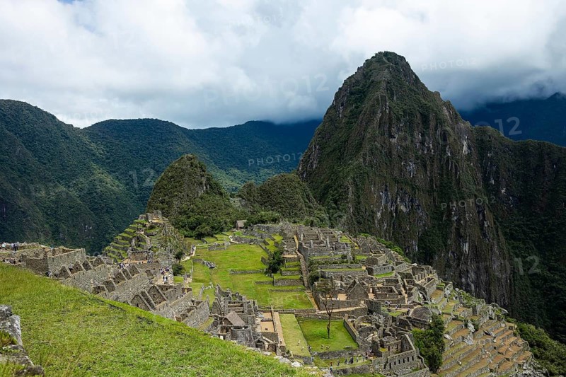 A breathtaking view of the ancient Inca city of Machu Picchu in Peru, nestled between lush green mountains and swirling clouds