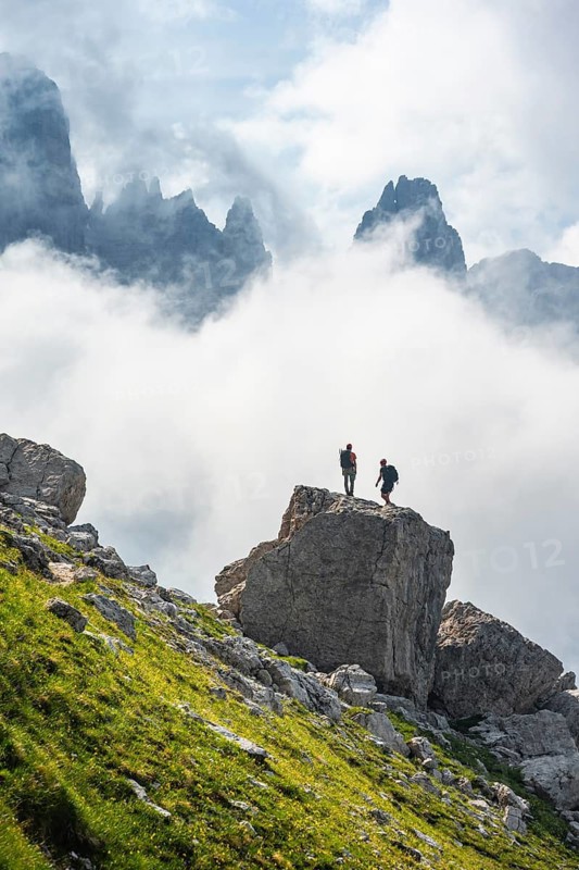 Alpine panorama, mountaineers on a large rock, fog and Torre Di Brentai and Cima Tosa, rocky mountain peaks and mountain landscape, Brenta Mountains, Parco Naturale Brenta-Adamello, Trentino, Italy