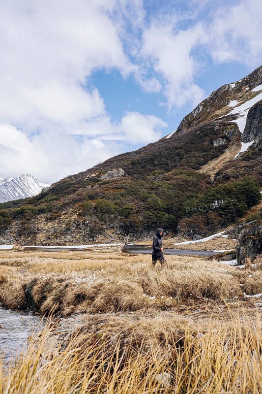 Woman hikes through grassland, Glaciar Vinciguerra, Ushuaia, Tierra del Fuego Province, Argentina, Ein Wanderer läuft durch eine bergige Landschaft mit dichter Vegetation und fließendem Wasser, Argentinien