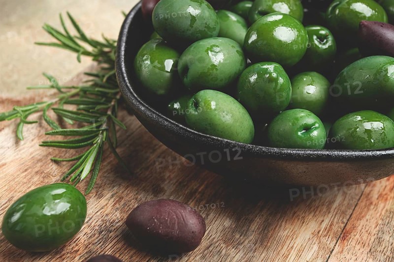 Chalkidiki olives, classic Greek green olives, in a bowl on a cutting board, top view, without people