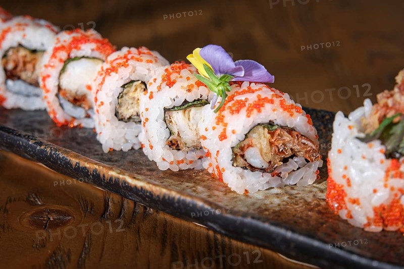 Delicious soft shell crab uramaki sushi rolls are garnished with masago and edible flowers, plated for elegant dining