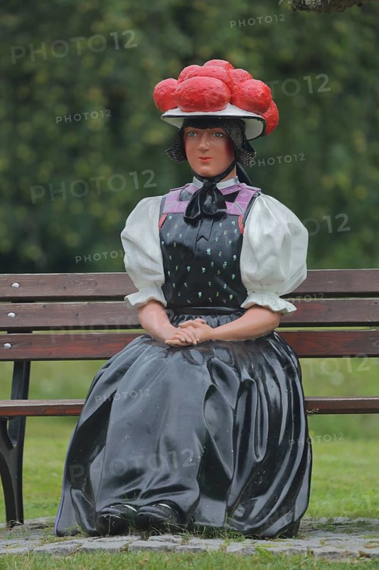 Doll in woman's traditional costume with Bollenhut on bench, Black Forest, Bollenhut, clothing, skirt, tradition, traditional, sitting, park bench, sculpture, flower decoration, Gutach-Black Forest railway, Ortenau, Southern Black Forest, Black Forest, Baden-Württemberg, Germany