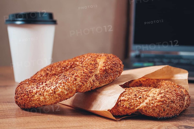Simits with coffee on a wooden table, with a laptop, in a cozy working environment, snack, breakfast, no people