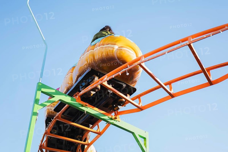 Close-up of a roller coaster ride on a bright orange track, set against a clear blue sky, capturing the thrill and excitement of amusement parks in vibrant colors